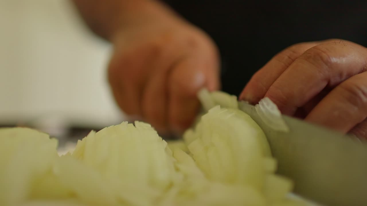 Slicing and dicing fresh, organic onions with a chef's knife - close up isolated side view