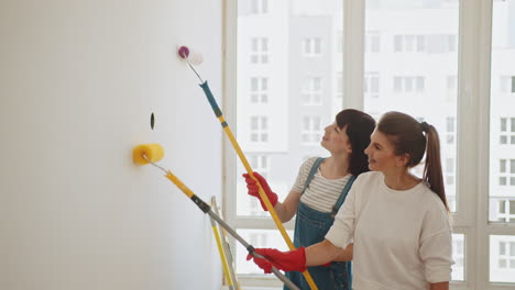 two women painting a wall