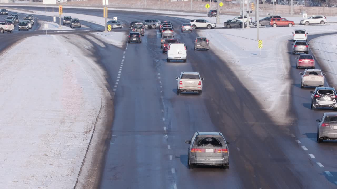 Cold vehicles slowly approach large suburban intersection in winter
