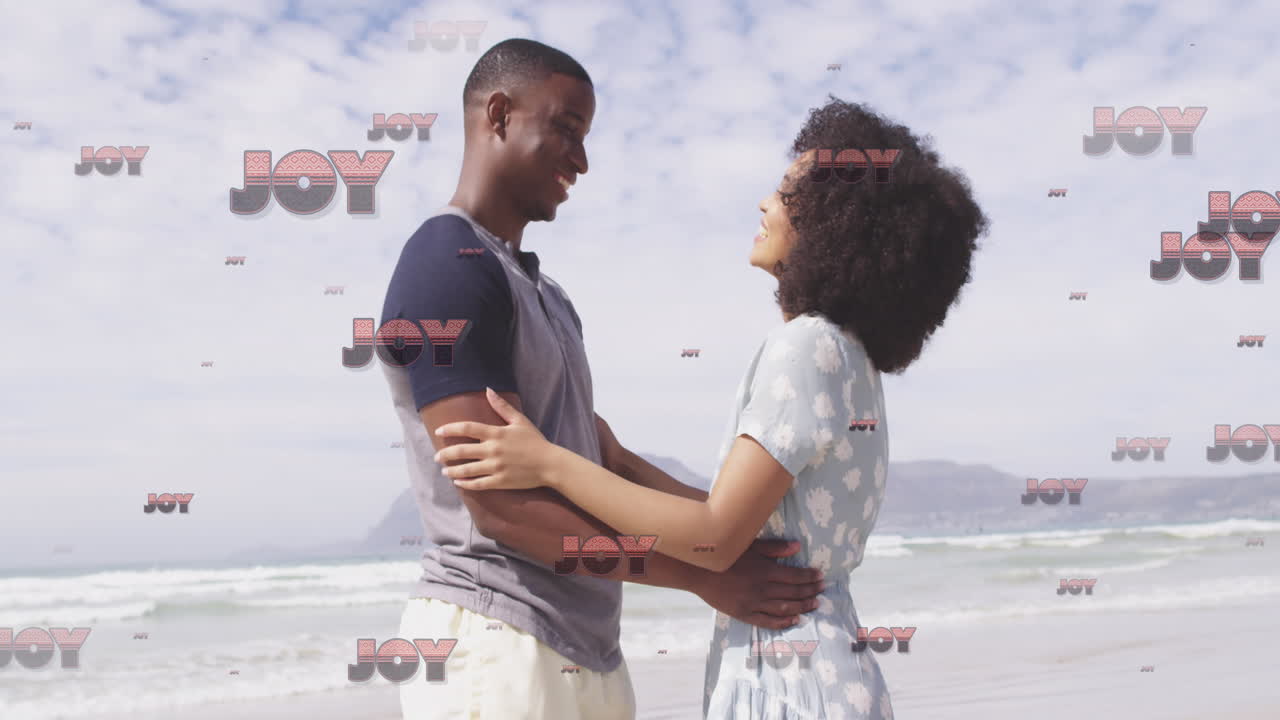 Couple embracing on beach with JOY text animation over them