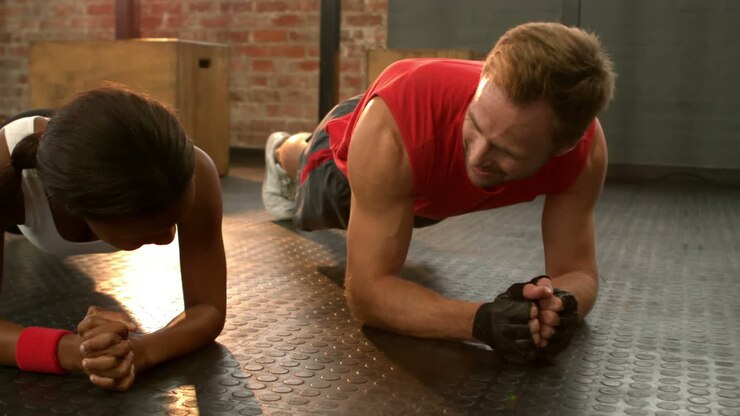 Fit man going plank exercises with trainer