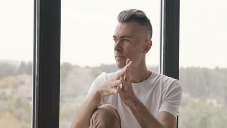 pensive man sitting at window thinking and worrying about something