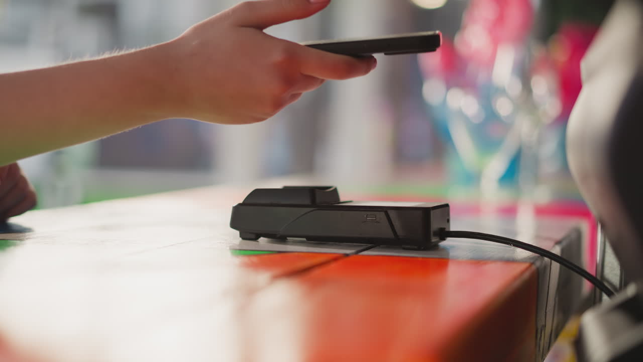 mujer toca la terminal pos con el teléfono móvil en la tienda de primer plano. el cliente utiliza la tecnología de pago digital para comprar bienes en la tienda. servicio bancario