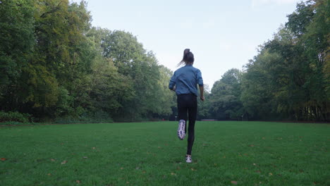 Mesmerizing-slow-motion-shot-of-a-woman-running-over-a-grassy-field,-with-the-camera-gracefully-following-her