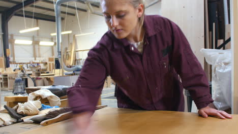 female apprentice finishing wood in carpentry workshop