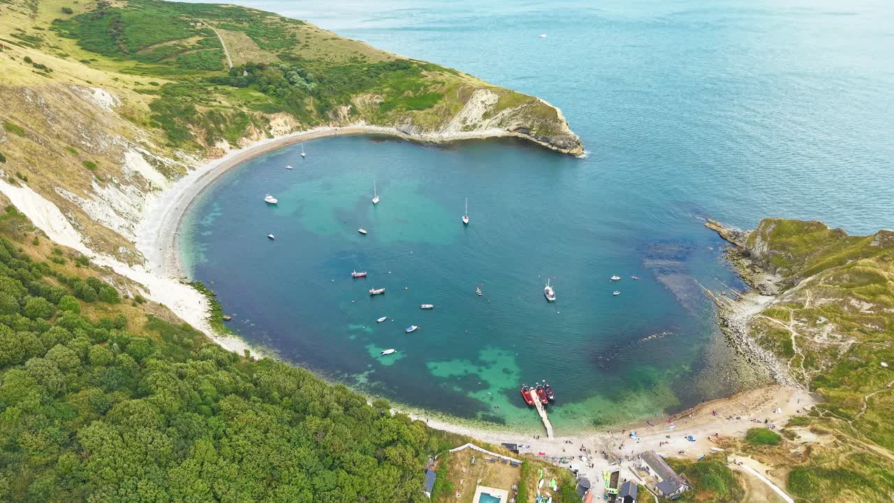 Drone shot of the beautiful coastline and clear water of Lulworth Cove, UK