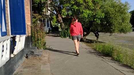 Woman-is-seen-from-behind-walking-along-the-river-Thames,-London