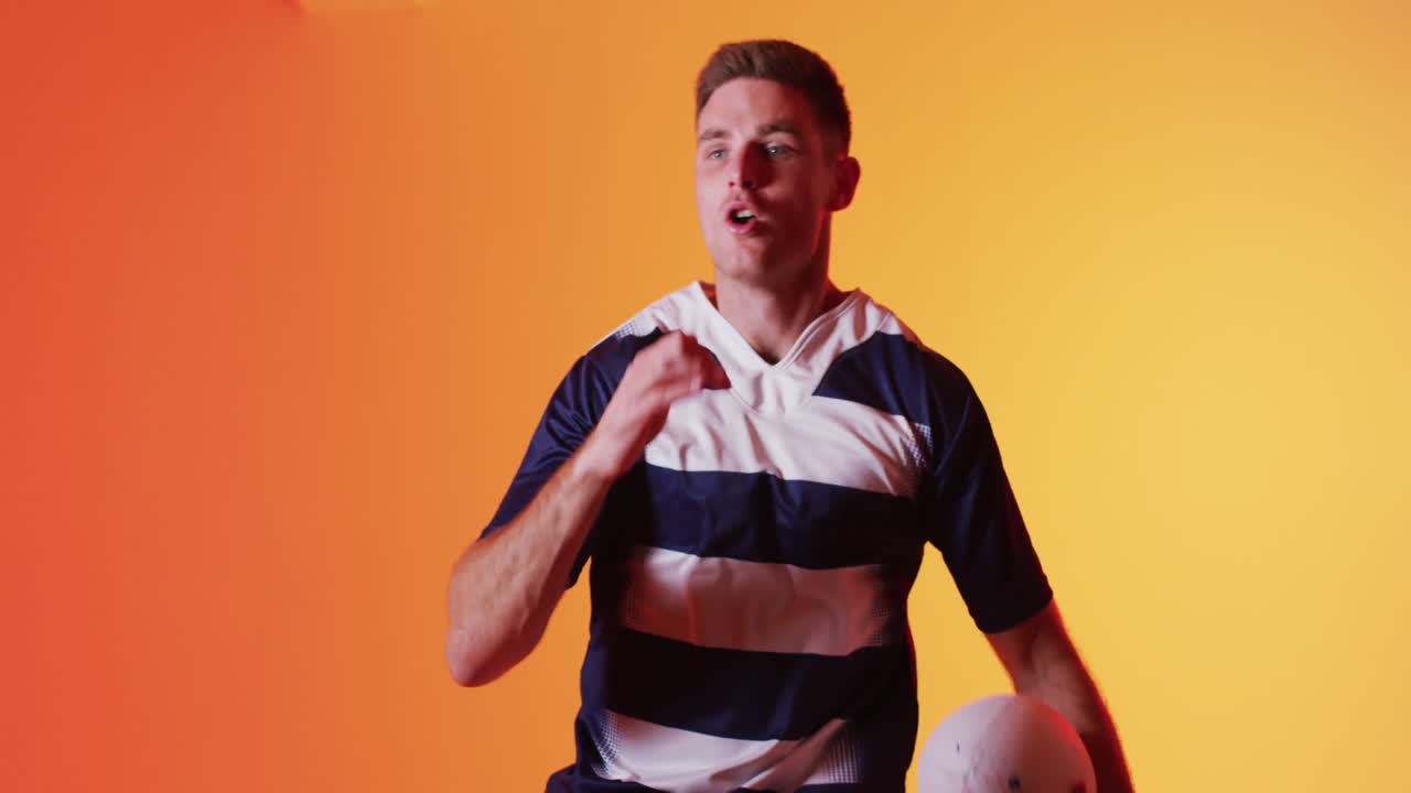 오렌지색 조명 위에서 럭비 공을 들고 달리는 백인 남성 럭비 선수의 초상화