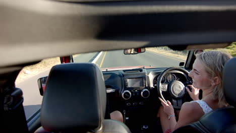 Young-Caucasian-woman-driving-a-car-on-a-sunny-day-on-a-road-trip,-with-copy-space