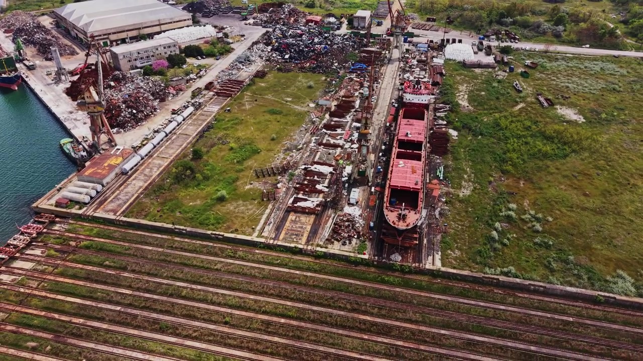Alte Schiffe liegen auf einem Werftgelände in der Nähe eines Uferbereichs in einem belebten Hafen festgemacht.