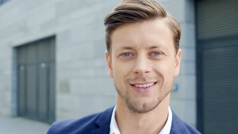 smiling businessman posing at camera on street. executive standing outside