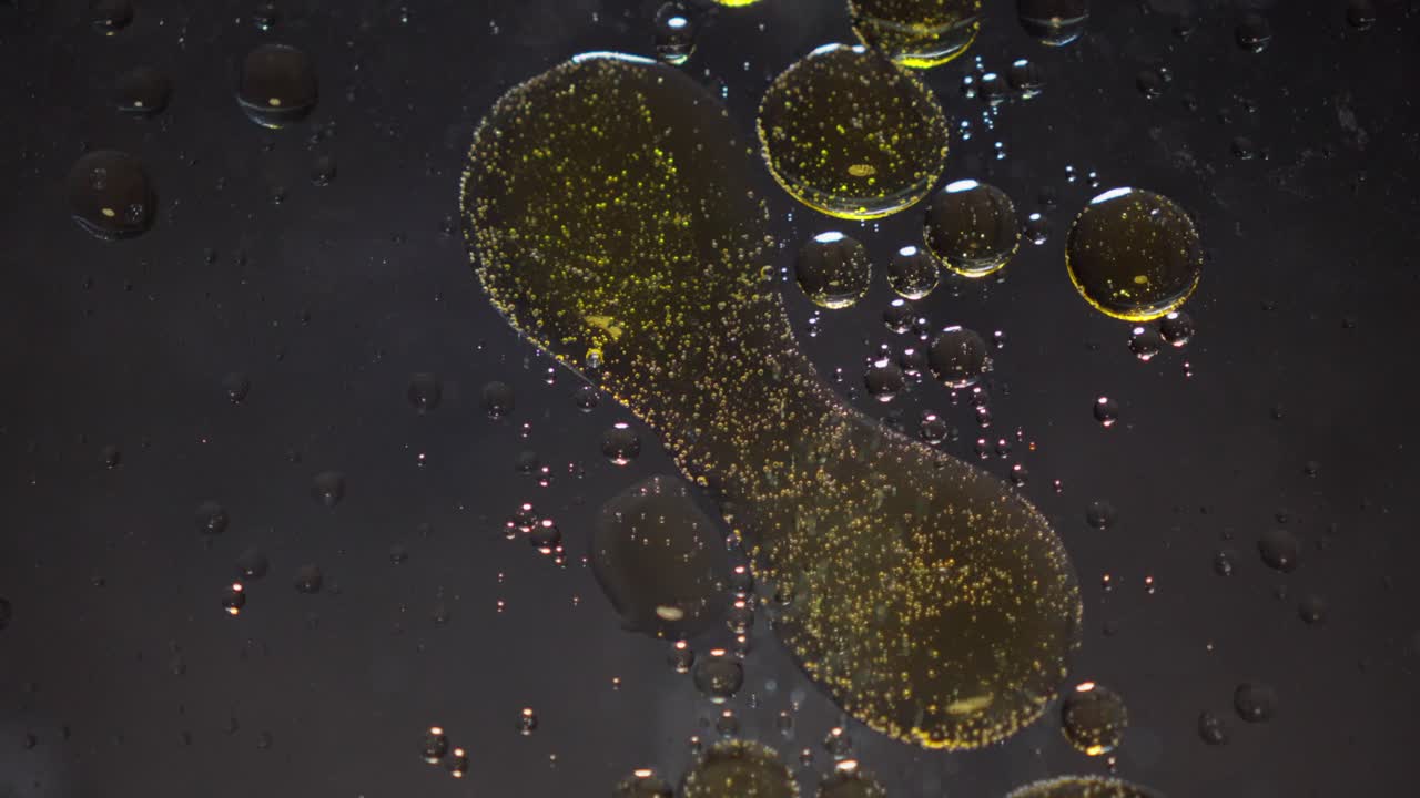 Glittering golden liquid, bubble shapes, spreading patterns, slow motion