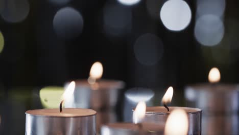 video of tea candles with white flames and copy space with bokeh on black background