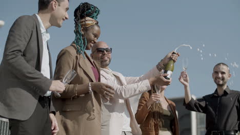 side view of happy colleagues opening champagne during party