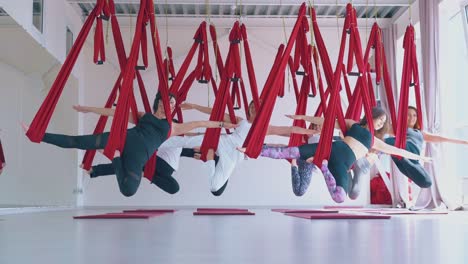 El-Equipo-De-Mujeres-Fuertes-Cuelga-En-Hamacas-Especiales-De-Yoga-Con-Mosca-Roja.