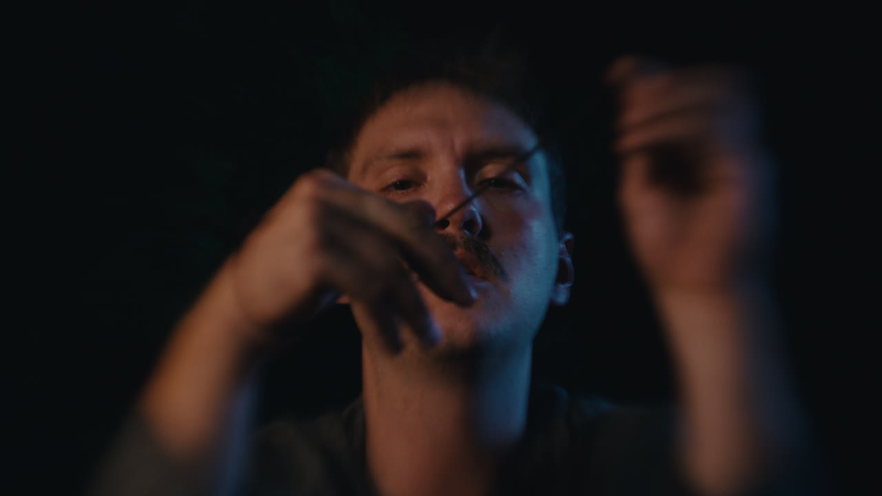 Man with Mustache Manipulating a String in Low Light