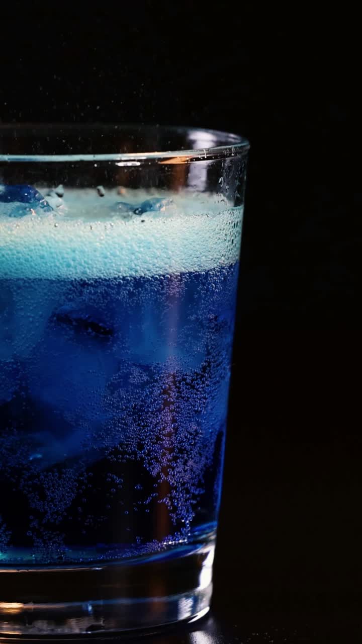 Bevanda blu effervescente con ghiaccio nel bicchiere