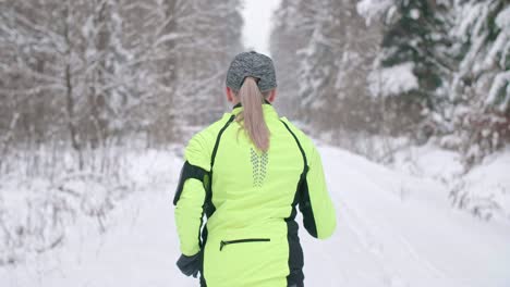 rear view of woman running in winter forest