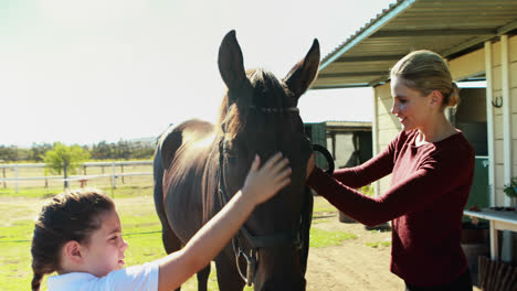 Mother-and-daughter-stroking-horse-in-ranch-4k