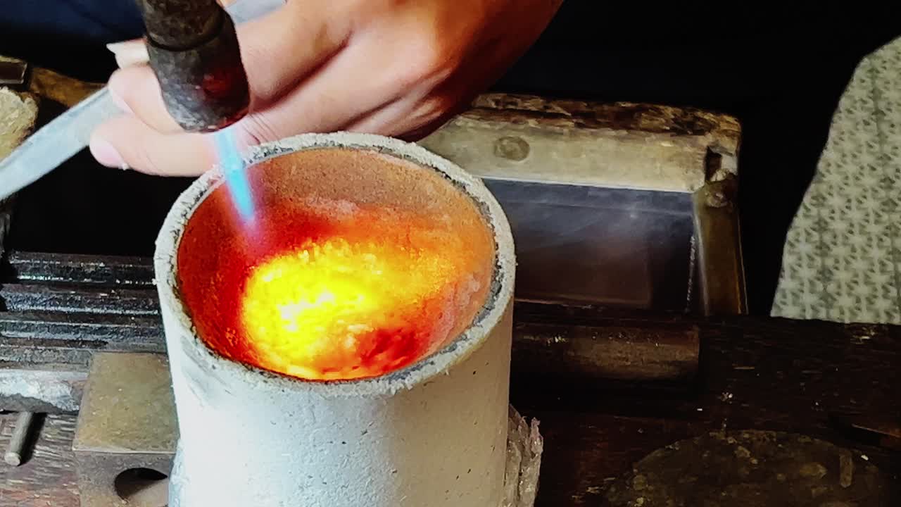 smith dropping gold metal pieces into the gold melting oven