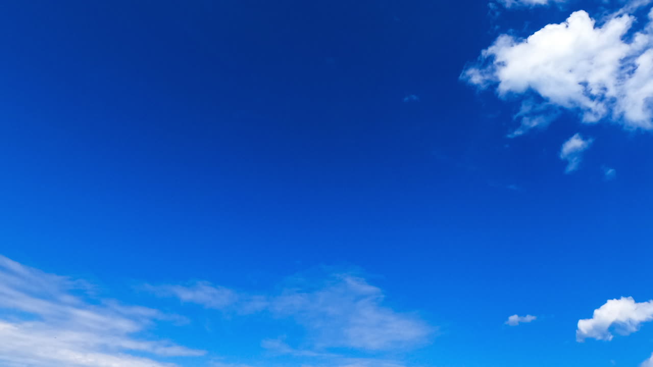 Beautiful azure sky with floating white soft clouds. Cumulus cloudscape changing into altocumulus. Low angle view. Timelapse.