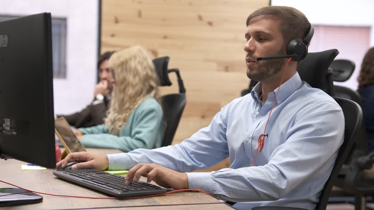 Confident businessman talking as he wears headset in coworking office