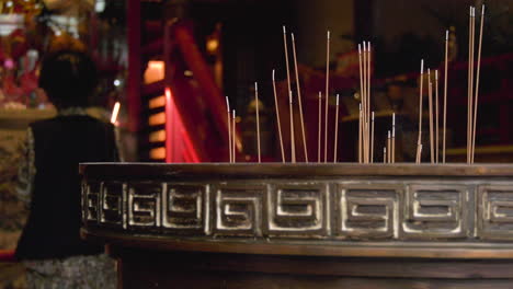 joss sticks burning with an elderly praying in the blurred background in a temple in chinatown, singapore