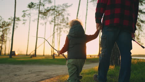 Un-Niño-Lindo-Y-Pequeño-Está-Cogido-De-La-Mano-De-Su-Abuelo-O-De-Su-Padre-Caminando-Juntos-Para-Pescar-Al-Atardecer