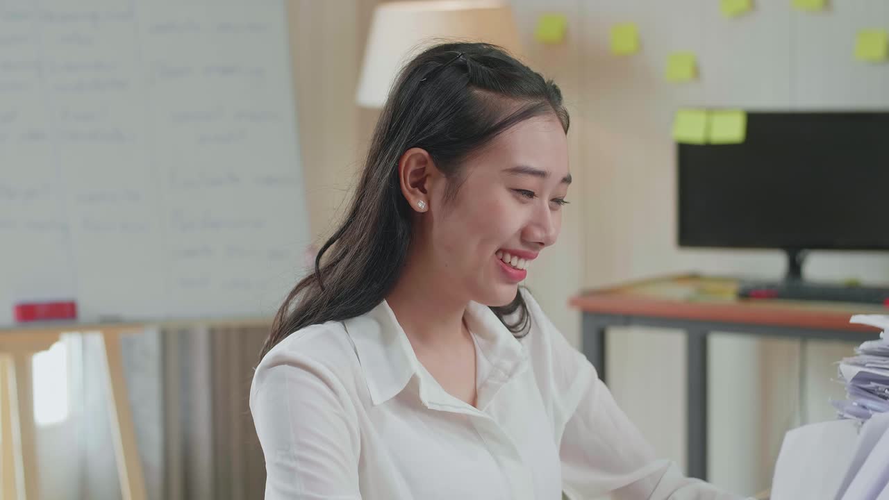 Close Up Of Asian Woman Smiling To Camera While Working With Documents At The Office