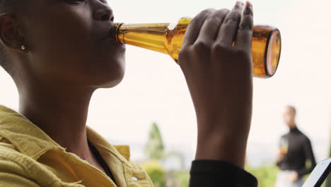 jonge afrikaans-amerikaanse vrouw drinkt bier op een dak.