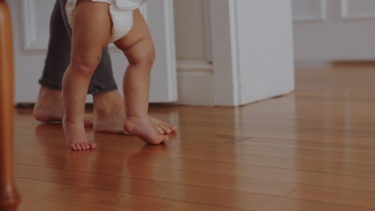 cerca de los pies bebé aprendiendo a caminar niño pequeño dando sus primeros pasos con los padres ayudando al bebé enseñando al niño en casa