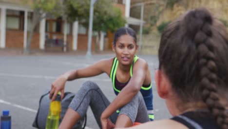 Diverso-Equipo-De-Baloncesto-Femenino-Sentado-En-El-Suelo-Y-Hablando