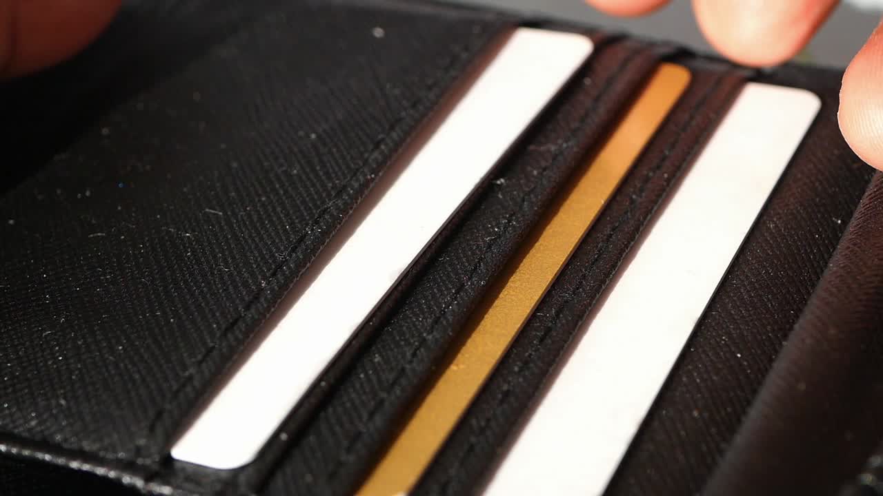 검은 지갑 에 신용 카드 를 넣는 손