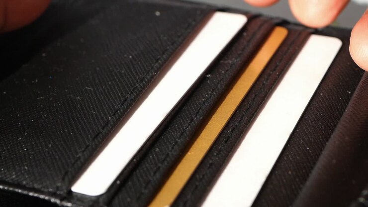 Hands Inserting Credit Cards into a Black Wallet