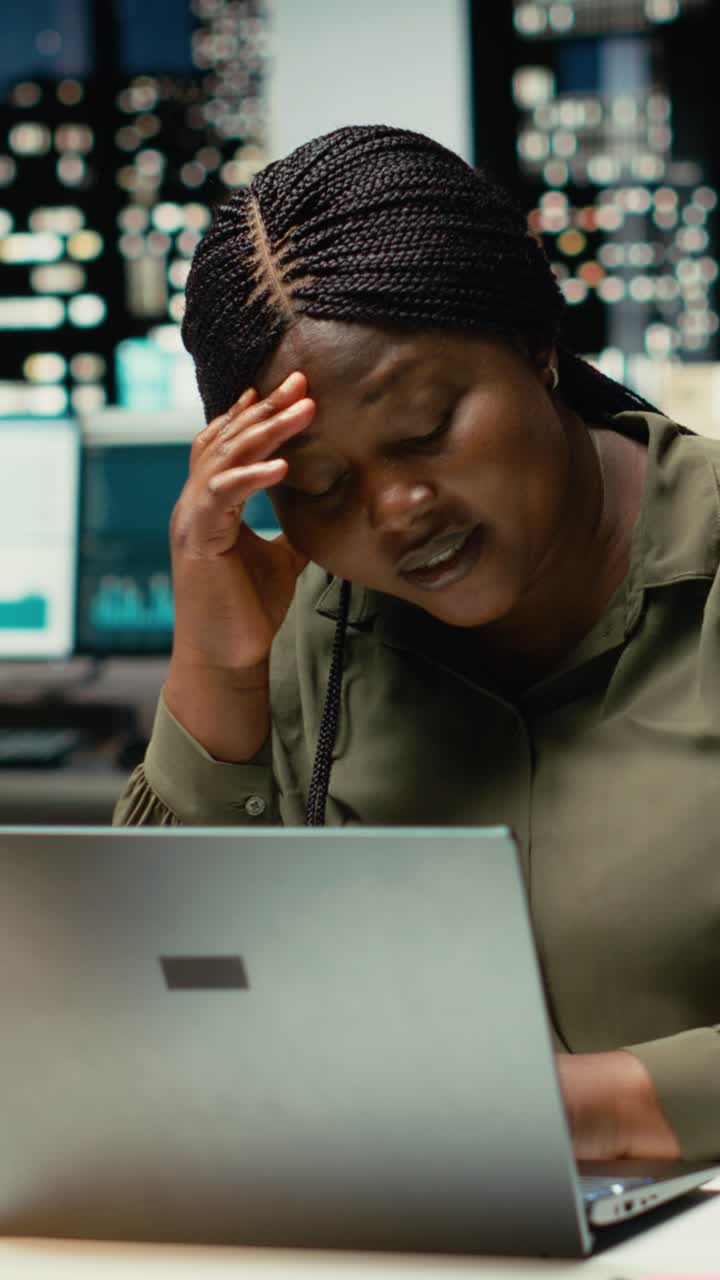 Afroamerikanische Frau im vertikalen Video bemerkt, dass sie spät nachts alleine im Büro arbeitet