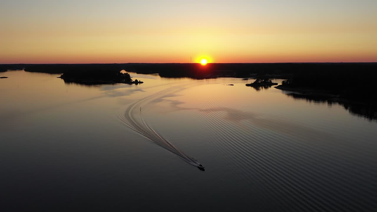 Aerial view of a boat, driving between islands, calm, summer sunset, in Tammisaari Archipelago, Uusimaa, Finland - reverse, drone shot