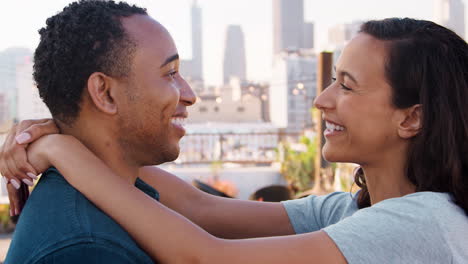 Romantic-Couple-Hugging-On-Rooftop-Terrace-With-City-Skyline-In-Background