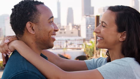 una pareja romántica abrazándose en la terraza de la azotea con el horizonte de la ciudad en el fondo