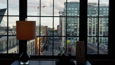 push in shot shot of city street through the windows of an apartment building downtown