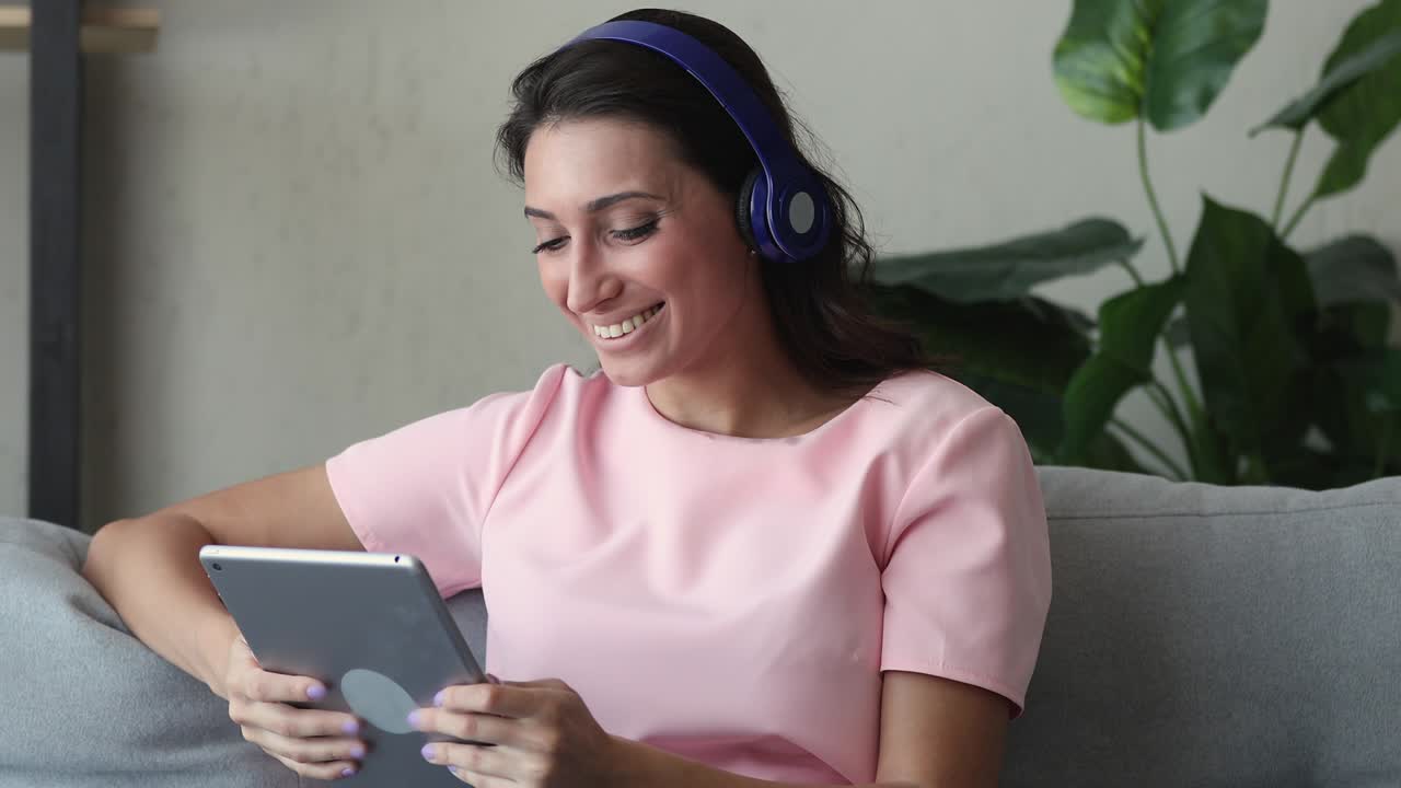 mujer usa auriculares saluda a un amigo por videocall usando un gadget de tableta