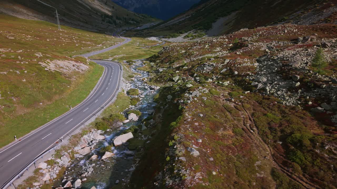 Winding road and creek in the Julier Pass, a high mountain pass in the Graubünden canton, Switzerland. Aerial drone