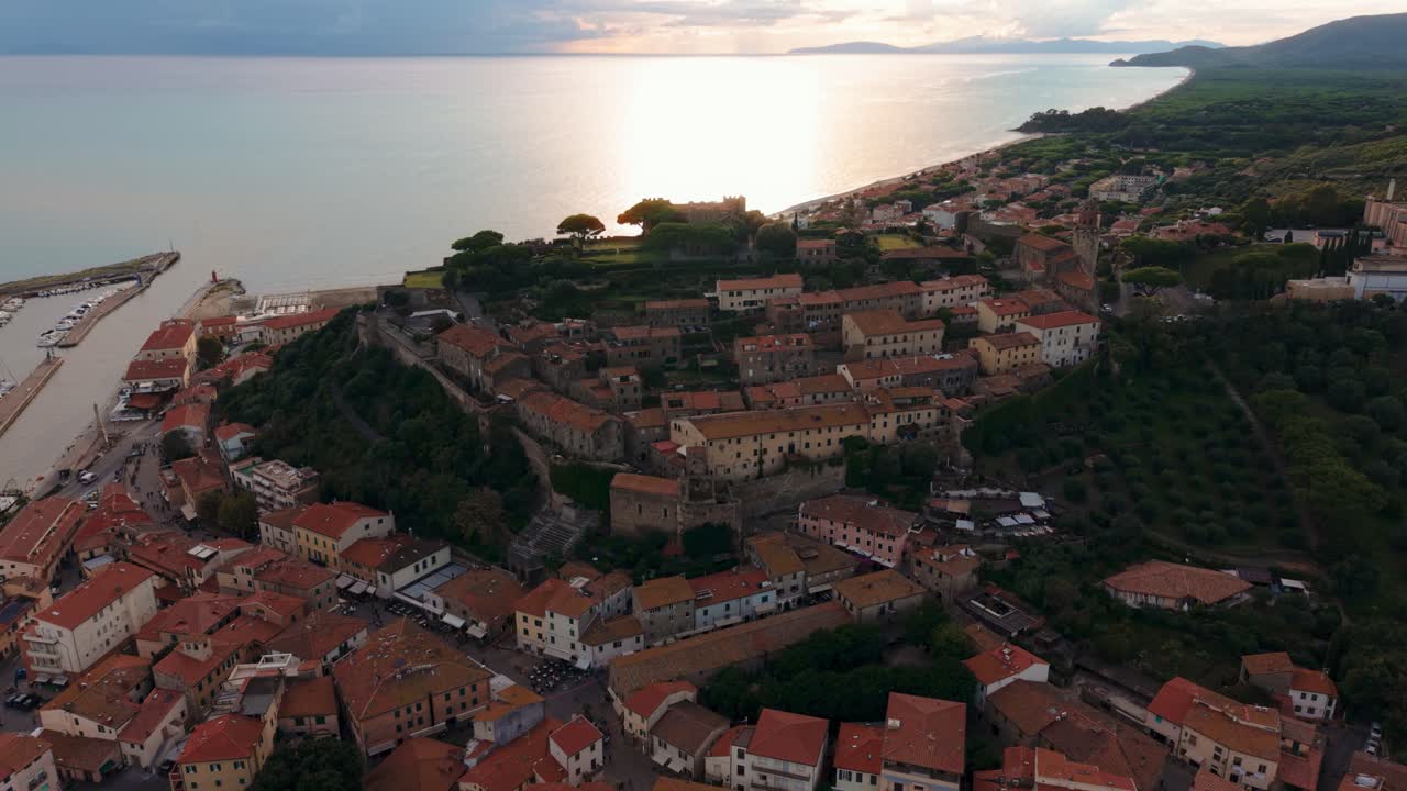 Castello di Castiglione della Pescaia con riflessi dorati sul mare nel tardo pomeriggio. Sorvolo aereo