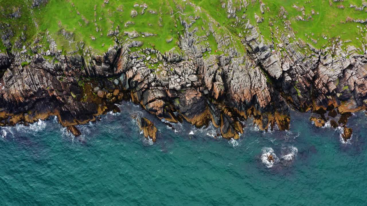 Aerial Standstill Top Down View Of Clogherhead Cliffs With People Relaxing On The Green Pasture Over Rugged Rocks