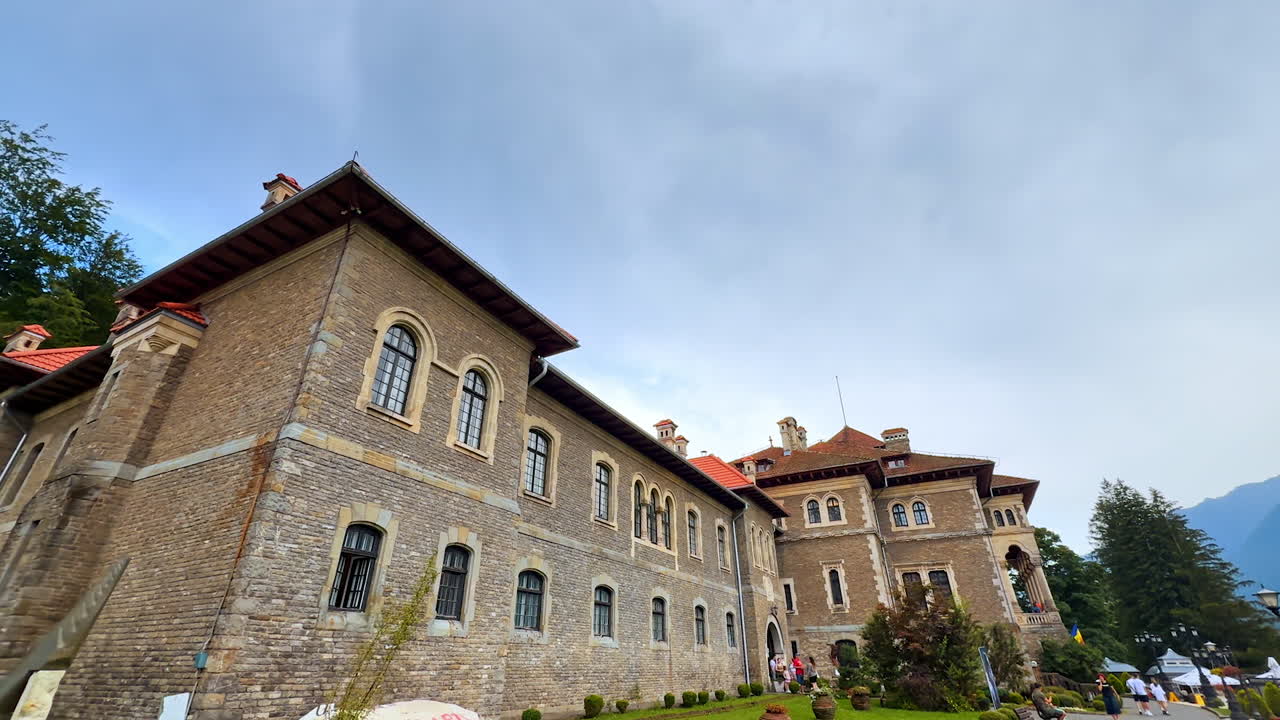 Busteni, Romania, 17 July 2025: Historical building of Cantacuzino Castle in Busteni, Romania. People walk around the landmark and enter the castle