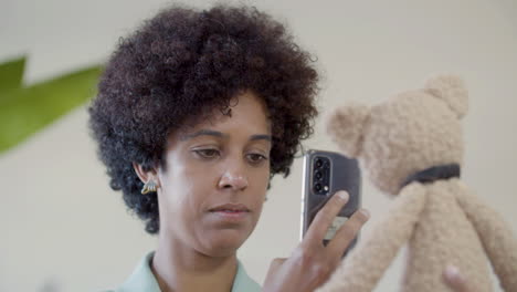 young lady taking picture of teddy bear toy