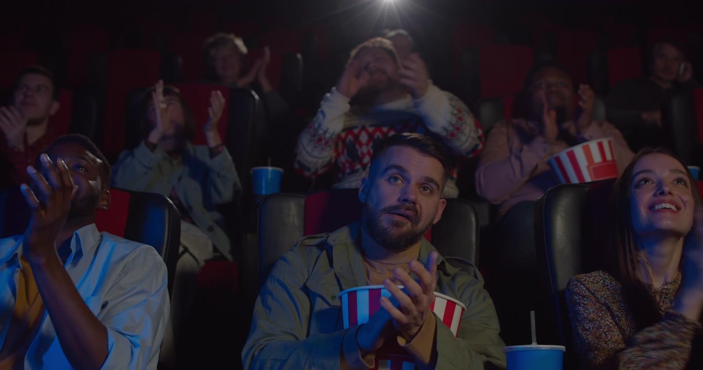 Público Diverso Aplaudindo Durante Exibição de Filme no Cinema