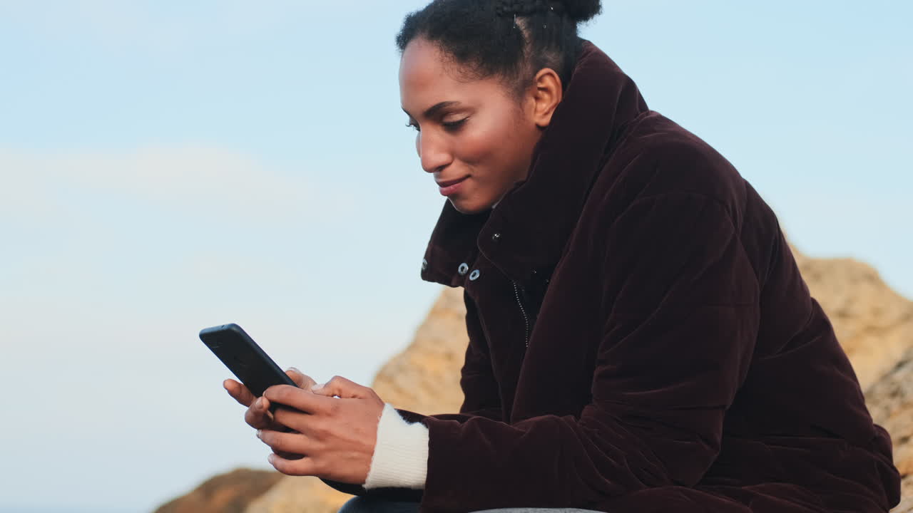 una chica afroamericana usando un teléfono móvil.