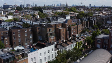 Forwards-fly-above-townhouses-in-urban-neighbourhood.-Tilt-up-revealing-of-cityscape-with-skyscrapers.-London,-UK