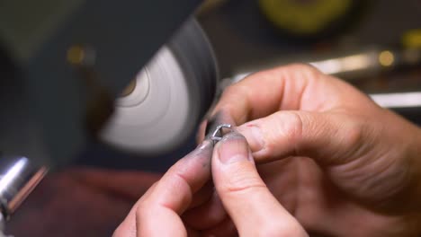 hands of male jewelry maker hand polishing and buffing a silver ring in a jewellery making workshop