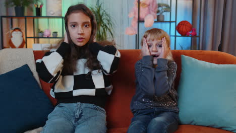 two girls are watching tv and are shocked by what they see